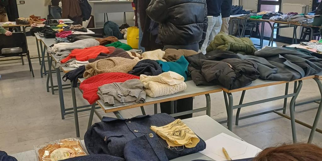 Persone che guardano i vestiti con in primo piano una ragazza che cuce una giacca da personalizzare